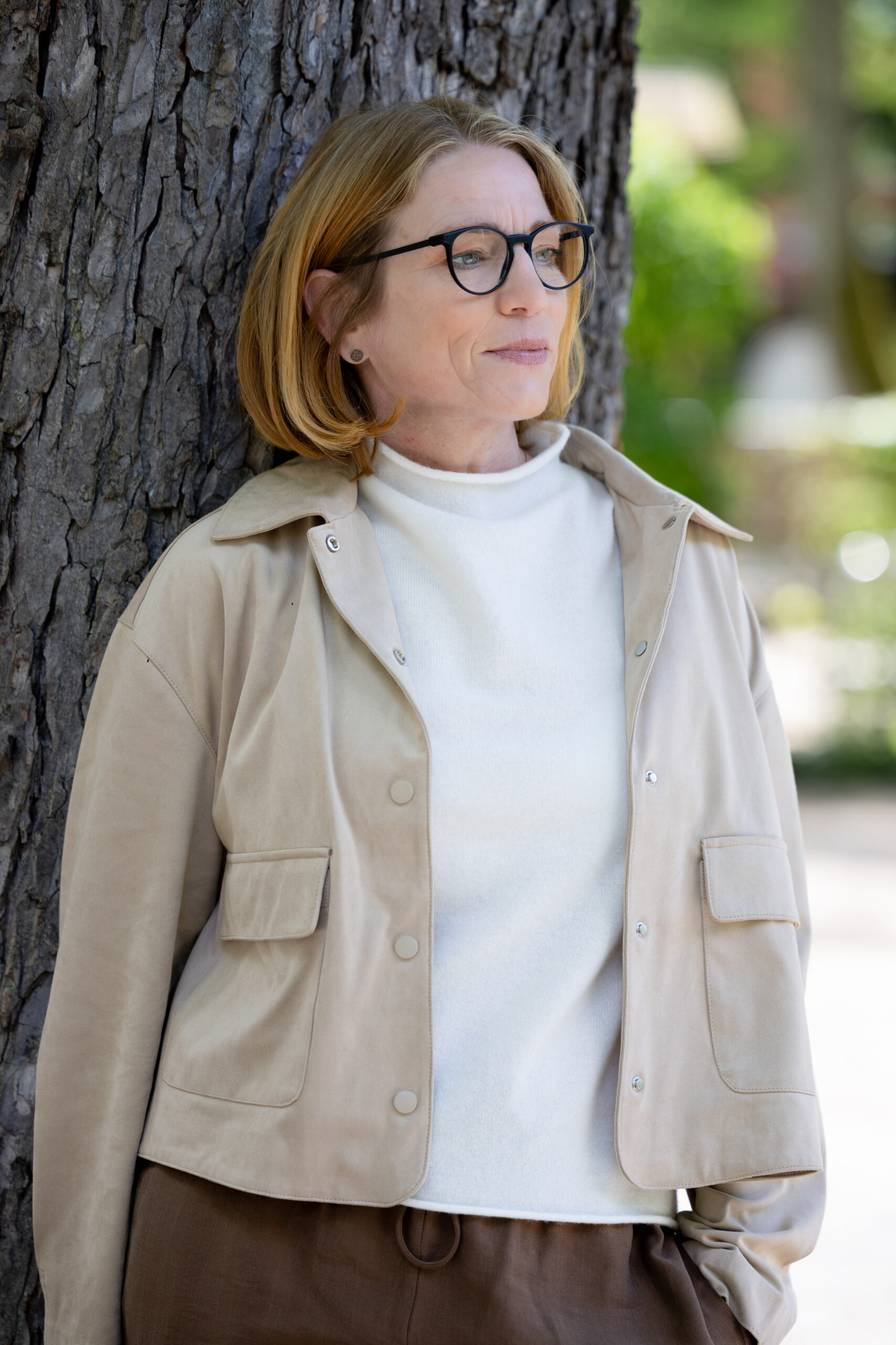 Sandra Werner, freie Rednerin, nachdenklich an einen Baum gelehnt
